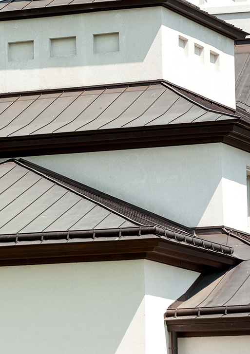 A close up of a house with a metal roof, showcasing the craftsmanship of a reputable roofing company.
