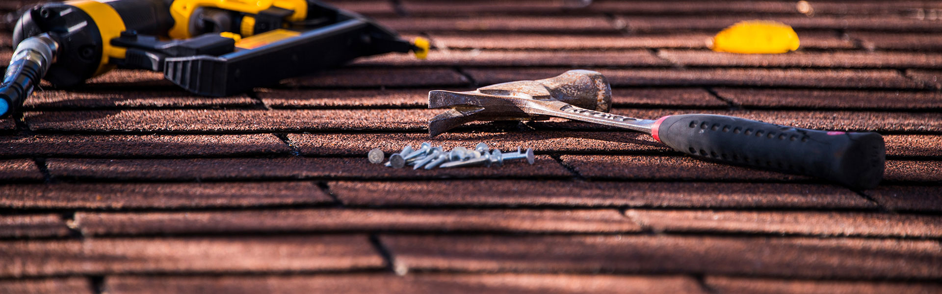 A residential roofing contractor in Dallas using a hammer and nails for roof repair.