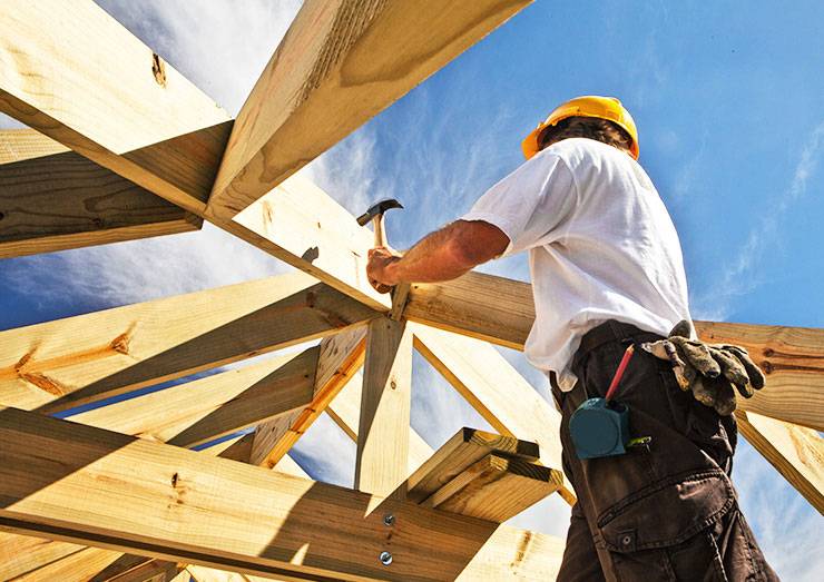 A construction worker is working on a residential roofing project, specifically a wooden roof.