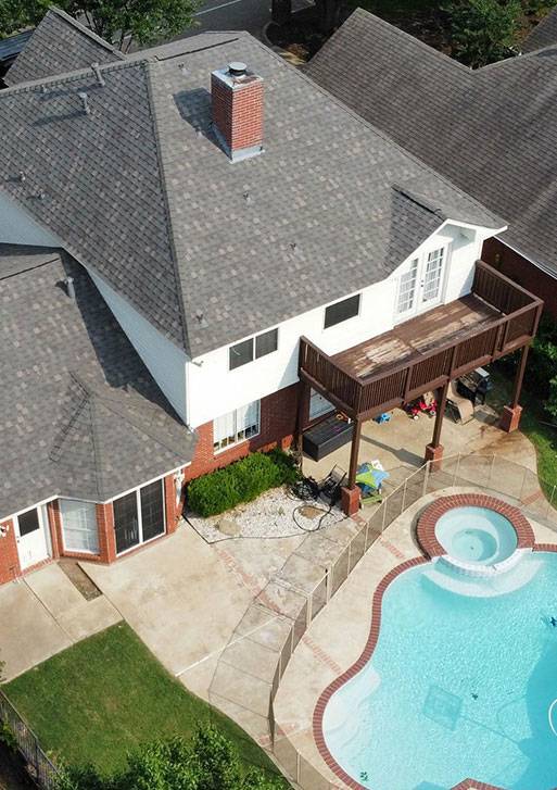An aerial view of a house with a swimming pool, showcasing the immaculate residential roofing.